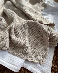 two white towels folded on top of each other next to a wicker basket filled with cloths