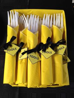 yellow napkins with black ribbon tied around them are arranged in a box on a table