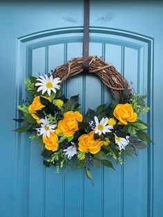 a wreath with yellow and white flowers hanging on a blue door