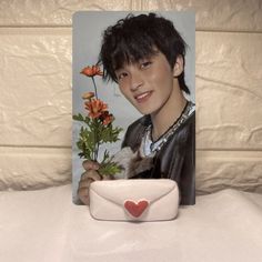 a young man holding flowers in front of a photo frame with a heart on it