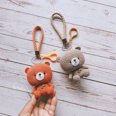 two crocheted teddy bears sitting next to each other on a wooden table with scissors