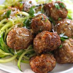 meatballs and zucchini on a white plate with parmesan cheese sprinkles