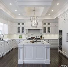 a large kitchen with white cabinets and an island in the middle of the room is lit by pendant lights