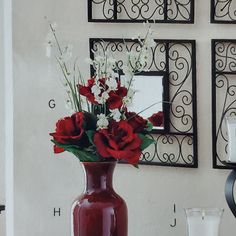 a vase filled with red and white flowers sitting on a table next to two mirrors