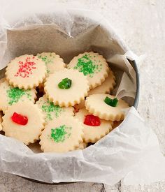 some cookies with green and red decorations in a tin