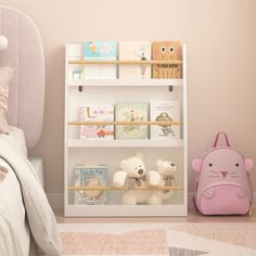 a child's bedroom with pink walls and white bookcases filled with books