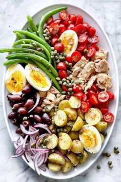 a white plate topped with eggs, tomatoes, green beans and other foodstuffs