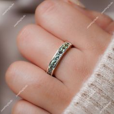 a woman's hand holding a ring with green stones on the inside of it