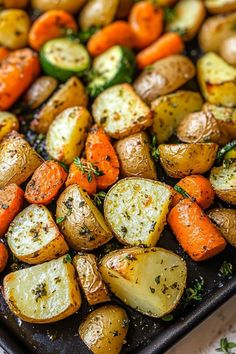 roasted potatoes and carrots with herbs on a baking sheet