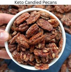 a person is holding a bowl full of pecans in front of the words keto candied pecans