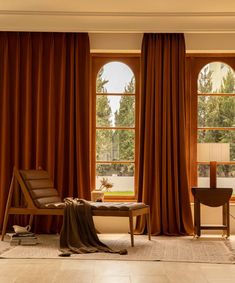 a living room filled with furniture and windows covered in brown draping next to a wooden table