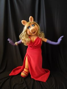 a woman in a red dress and purple gloves with her arms out, sitting on a black background