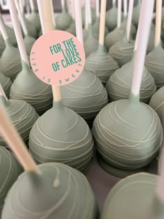 there are many green cake pops with white sticks sticking out of them and a pink sign that says for the love of cakes