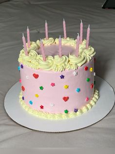 a pink birthday cake with white frosting and lit candles