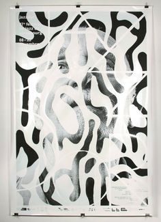 a black and white poster with an abstract pattern on it's back side, in front of a white wall