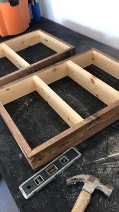 two wooden frames sitting on top of a black table next to a hammer and screwdriver