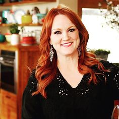 a woman with red hair is smiling for the camera while holding a wine glass in her hand