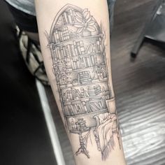 a black and white photo of a person's arm with a book shelf tattoo on it