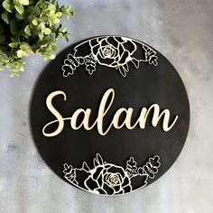 a black and white sign that says salam with flowers in the center on a wall