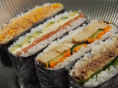 three sushi rolls with different toppings on top of each other in a metal plate