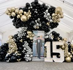 a large balloon arch is decorated with black, silver and gold balloons that spell the number fifteen