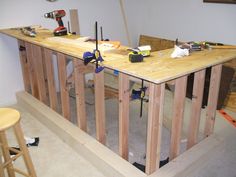 an unfinished kitchen counter being built with tools on the counter top and two stools