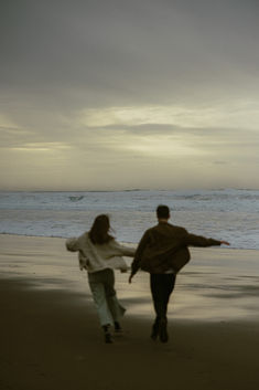 two people walking on the beach near the ocean