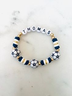 the blue and white bracelet with gold accents is shown on a marble countertop, it says thomas