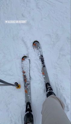 someone is standing in the snow with their skis on and feet propped up next to them