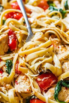 a close up of a pasta dish with chicken, tomatoes and spinach