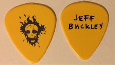 two yellow guitar picks with the words jeff backley written on one side and an image of a skull on the other