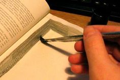 a person holding a pen and writing on an open book