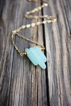 a necklace with a blue stone on it sitting on top of a wooden table next to a chain