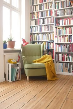 a green chair sitting in front of a book shelf filled with books