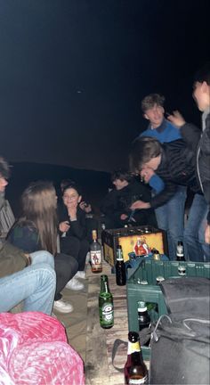 a group of people sitting around each other at a table with beer bottles on it