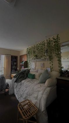 a bed sitting in a bedroom next to a window with plants on the headboard