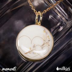 a white and gold necklace with two hearts in the center on a black background that says moments