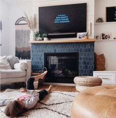 a little boy laying on the floor in front of a fireplace with a flat screen tv above it