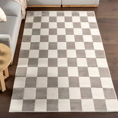 a living room with a checkered rug on the floor next to a gray couch