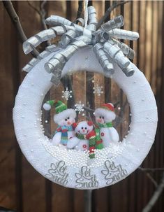 an ornament hanging from a tree with snowmen on it