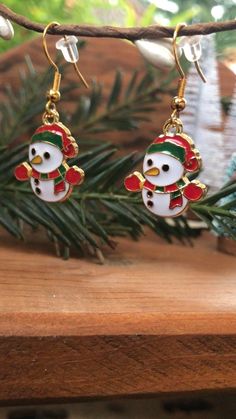 Festive Snowman with red and green scarf, hat, and mittens winter holiday gold dangly earrings.  How cute are these little Fosty Snowman earrings?? They give all the Cozy Christmas vibes and are perfect for the Holidays. 🎄 Perfect for gifting to Wife, Girlfriend, Mom, Sister, Auntie, Teacher, or just treat yourself!  The Earring hooks are made with gold plated sterling silver and each pair comes with the clear rubber backings.   I make all my items with so much care, love, and joy and I hope you feel those vibes every time you wear one of my pieces! 🥰 Thank you so much for stopping by my shop. Please don't hesitate to message me with any questions. 😊💗 Cute Christmas Gift Earrings, Gold Earrings For Winter Holiday, Gold Earrings For Holiday Season, Winter Festive Dangle Earrings, Adjustable Earrings For Christmas Gift, Adjustable Earrings As A Christmas Gift, Red Earrings For Winter Gift, White Festive Earrings For Winter, Gold Earrings As Winter Gift