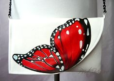 a white purse with a red butterfly painted on it