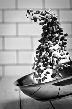 a metal bowl filled with nuts on top of a wooden table