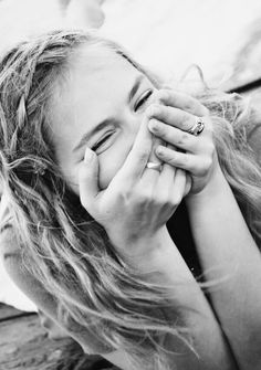 a woman covers her face with her hands while laying on the ground in black and white