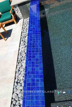 an empty chair sitting next to a pool with rocks and gravel on the ground in front of it