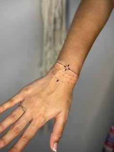 a woman's hand with a small tattoo on her left wrist and the other arm