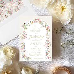 the wedding stationery is laid out on top of some white flowers and other items