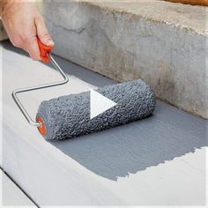 a person using a paint roller to paint a concrete block with gray and white colors