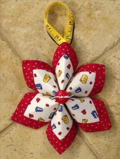 a red and white flower shaped ornament with measuring tape on the end of it