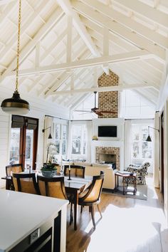 a dining room table and chairs in front of an open kitchen area with white walls